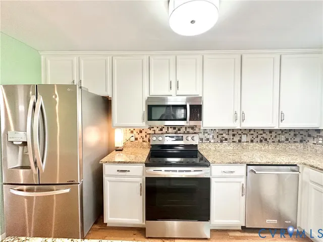 a kitchen with stainless steel appliances granite countertop a refrigerator a stove a sink a dining table and chairs with wooden floor