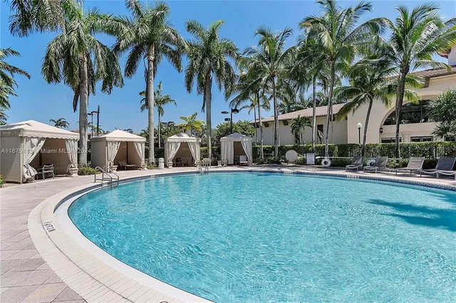 a view of a swimming pool with a lawn chairs under palm trees