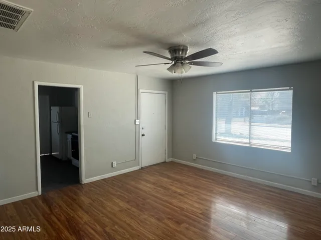 a view of empty room with wooden floor and fan
