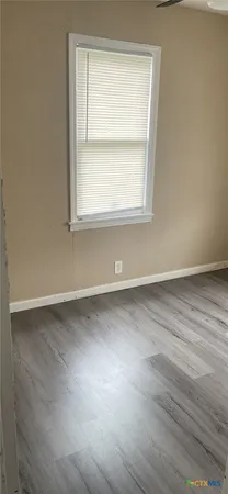 an empty room with wooden floor and a window