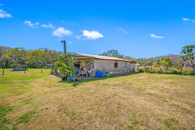 a view of a dining room and livingroom with furniture wooden floor a rug a flat screen tv a painting and a chandelier