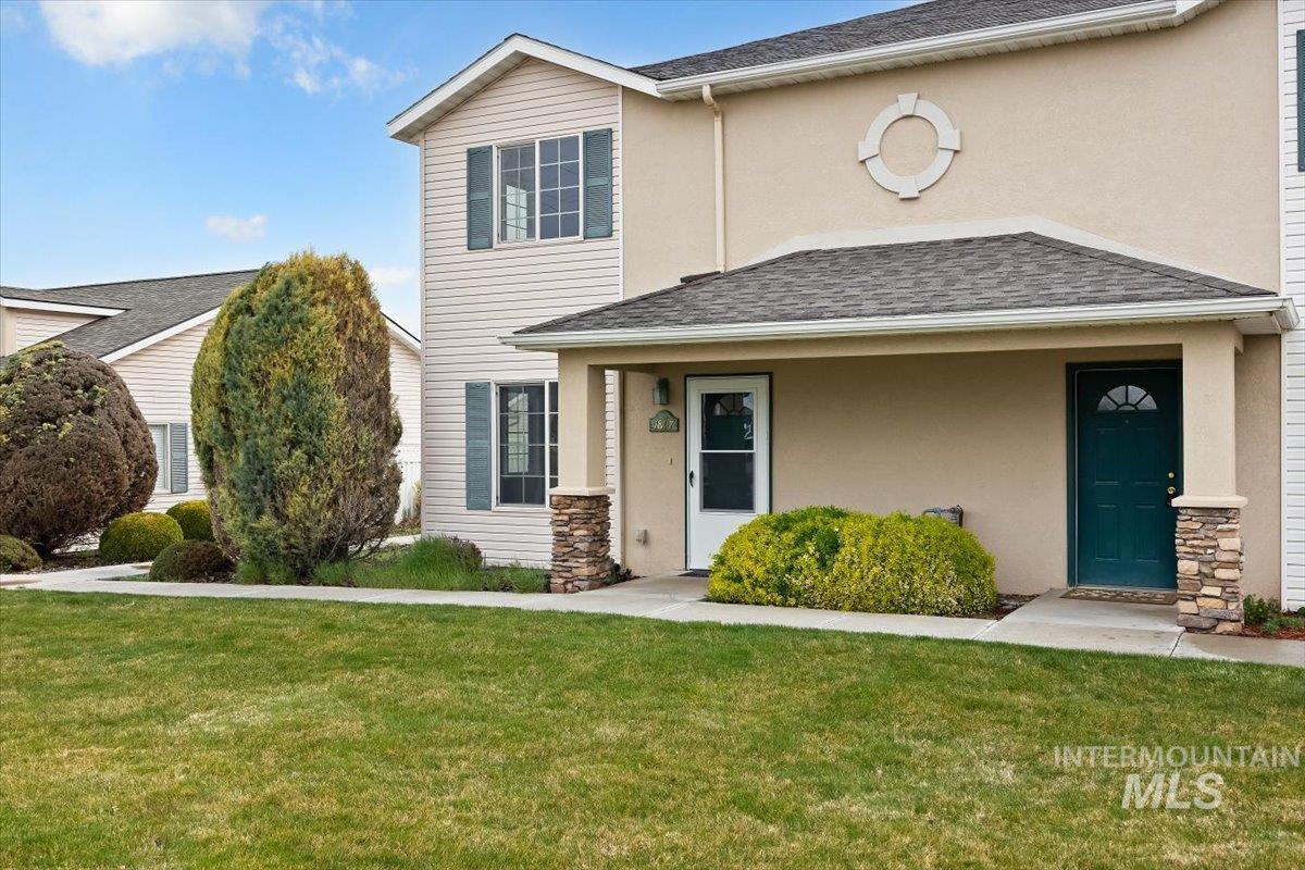 View of front of house with a front lawn, stucco siding, and stone siding