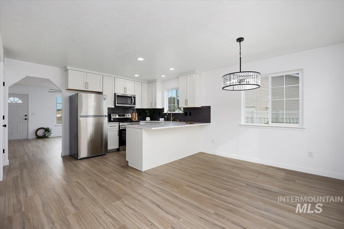 1897 Hampton Way Twin Falls, ID 83301 - Photo 11 of 48 Kitchen featuring stainless steel appliances, a peninsula, light countertops, backsplash, and white cabinetry