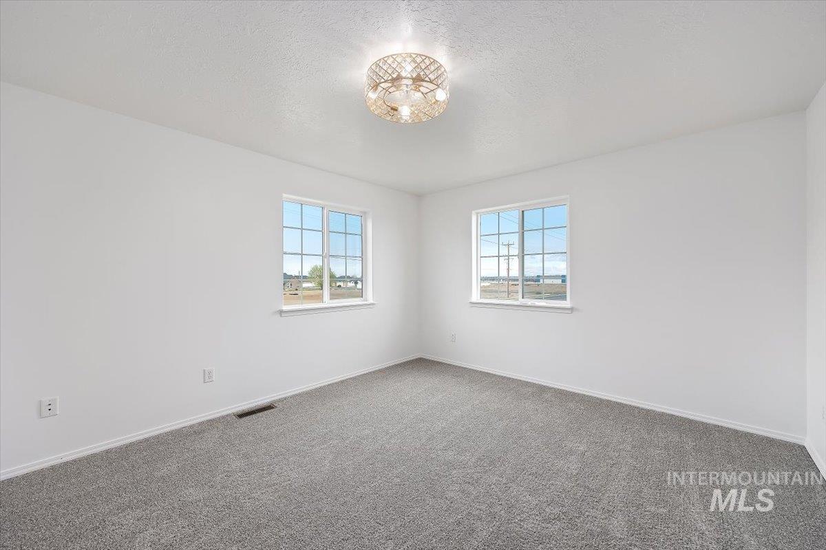 1897 Hampton Way Twin Falls, ID 83301 - Photo 17 of 48 Empty room featuring plenty of natural light, a textured ceiling, and dark colored carpet