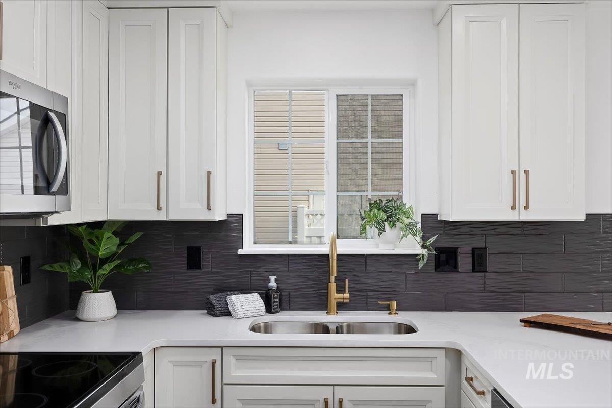 1897 Hampton Way Twin Falls, ID 83301 - Photo 5 of 48 Kitchen with light stone countertops, white cabinetry, stainless steel microwave, and range with electric stovetop