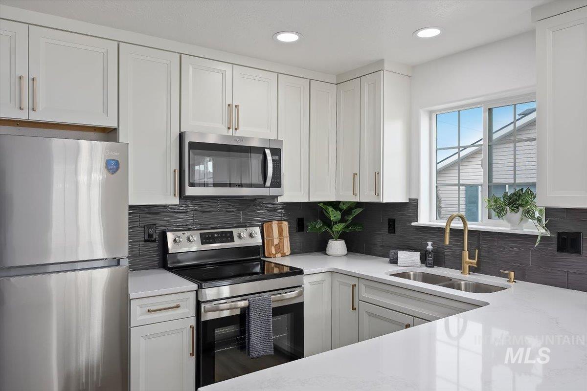 1897 Hampton Way Twin Falls, ID 83301 - Photo 7 of 48 Kitchen featuring stainless steel appliances, white cabinetry, backsplash, light stone countertops, and recessed lighting