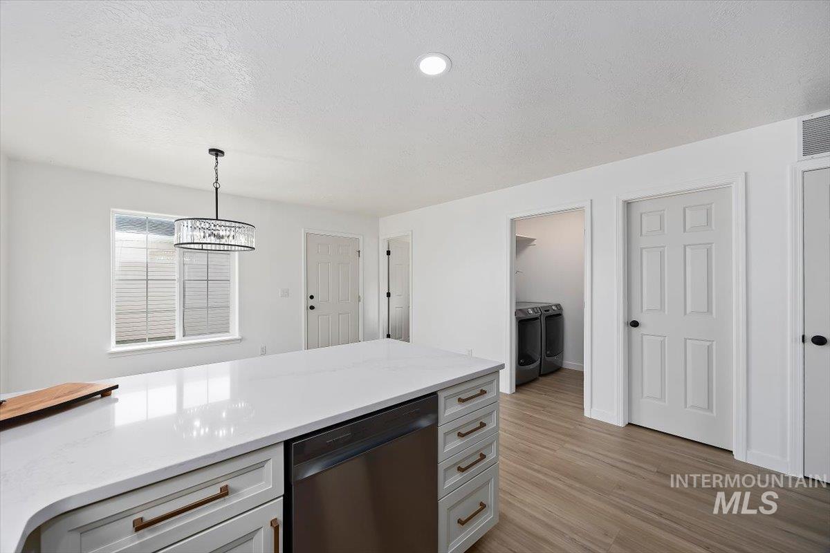 1897 Hampton Way Twin Falls, ID 83301 - Photo 10 of 48 Kitchen with washer and dryer, dishwasher, hanging light fixtures, light stone counters, and light wood-style floors