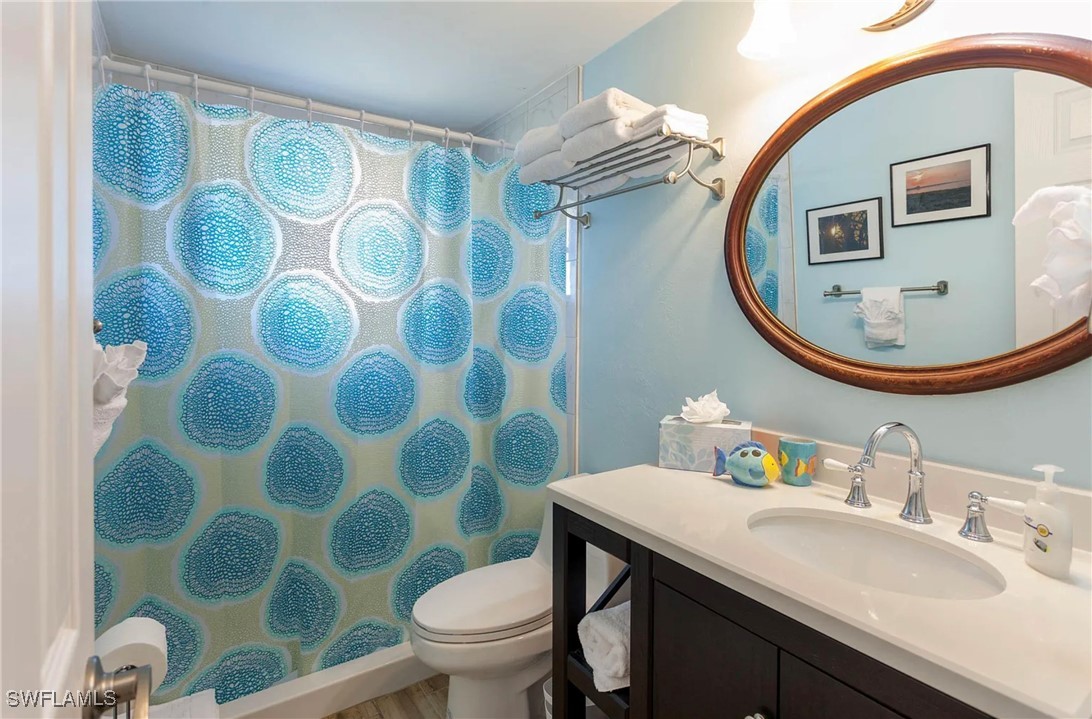 11093 Kelly Road Fort Myers, FL 33908 - Photo 11 of 12 a bathroom with a sink a mirror a toilet and a mirror