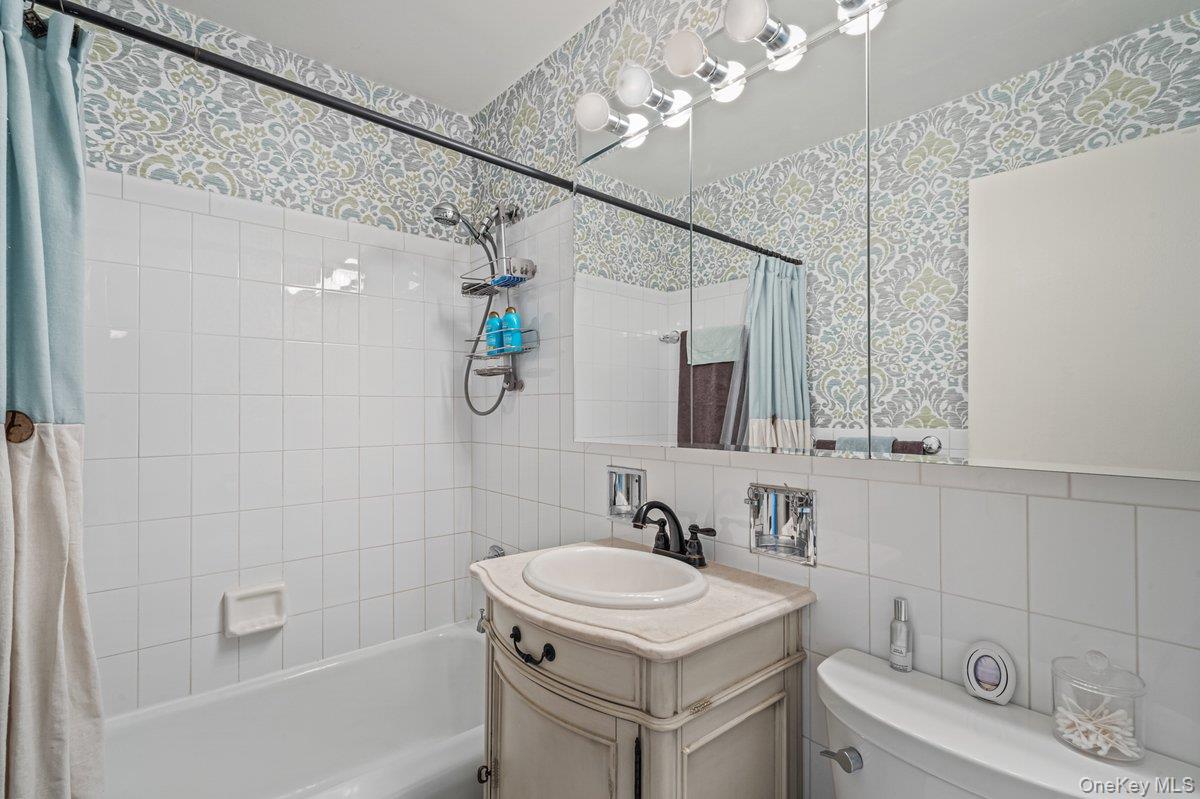 18-55 Corporal Kennedy Street, Unit 6H Queens, NY 11360 - Photo 12 of 18 Bathroom featuring wallpapered walls, vanity, shower / tub combo, and tile walls