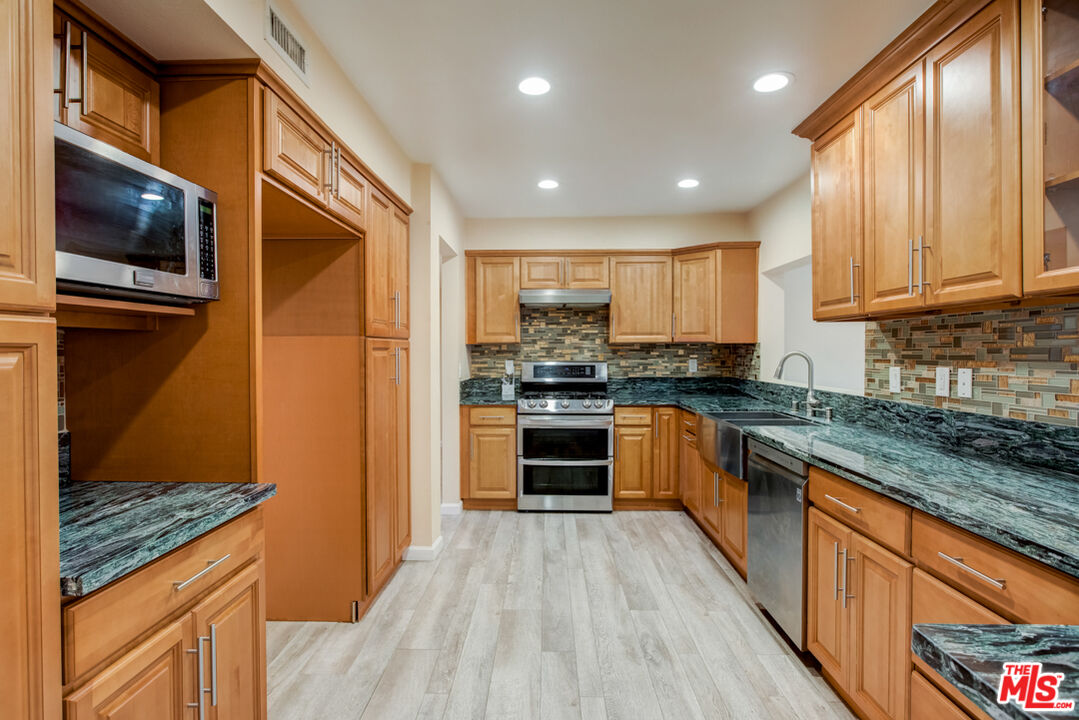 23620 Sunset Crossing Road Diamond Bar, CA 91765 - Photo 4 of 41 a kitchen with stainless steel appliances granite countertop wooden cabinets a stove top oven a sink and dishwasher a oven with wooden floor