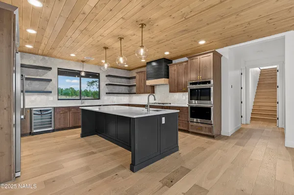 a large kitchen with stainless steel appliances kitchen island granite countertop a large counter top and wooden floors