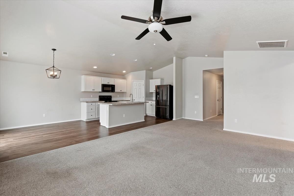 1685 Southwest Levant Way Mountain Home, ID 83647 - Photo 14 of 31 Unfurnished living room with dark colored carpet, a ceiling fan, recessed lighting, and lofted ceiling