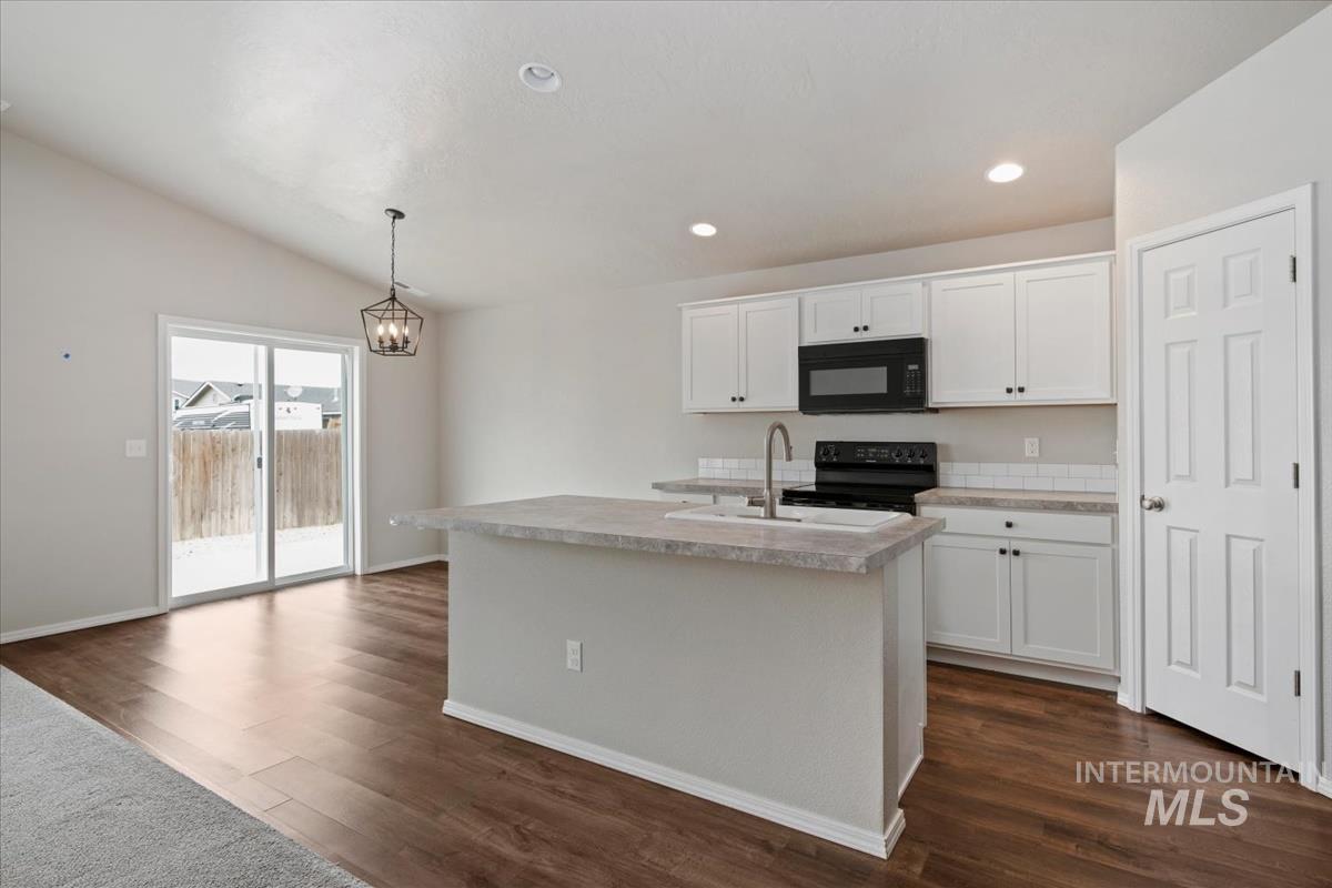 1685 Southwest Levant Way Mountain Home, ID 83647 - Photo 7 of 31 Kitchen with white cabinetry, light countertops, black appliances, a kitchen island with sink, and hanging light fixtures