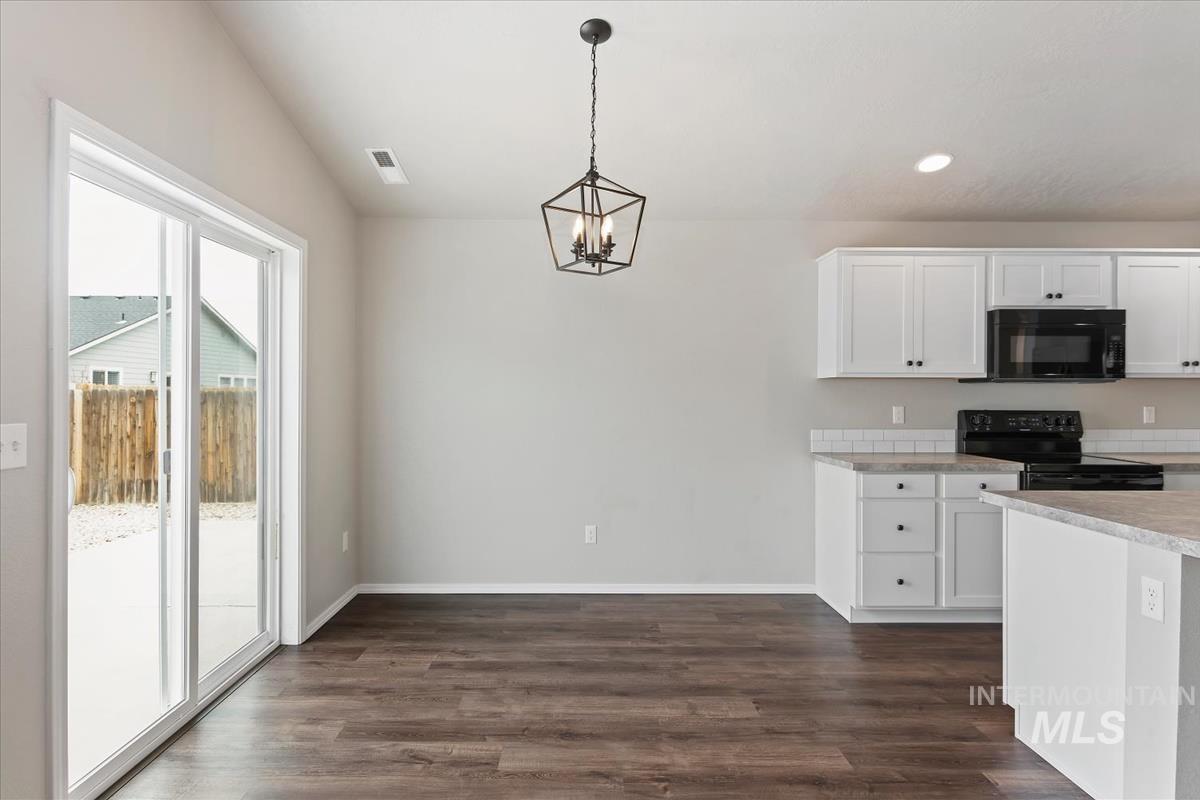 1685 Southwest Levant Way Mountain Home, ID 83647 - Photo 8 of 31 Kitchen with light countertops, black appliances, white cabinetry, dark wood finished floors, and lofted ceiling