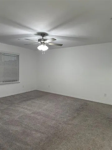 an empty room with chandelier fan and windows