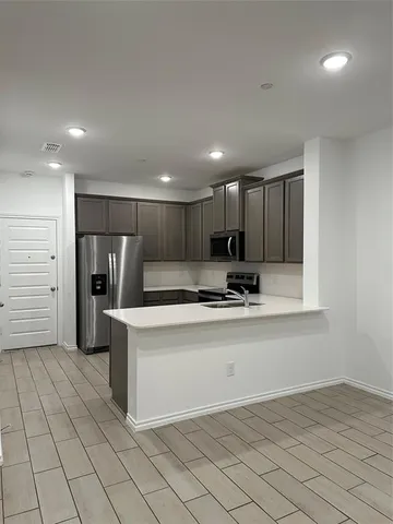 a view of kitchen with stainless steel appliances granite countertop a refrigerator and a sink