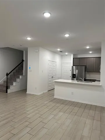 a view of an empty room and kitchen with furniture