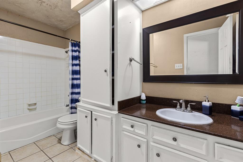 1502 Hinchliffe Road Mexia, TX 76667 - Photo 14 of 40 Bathroom featuring shower / bathtub combination with curtain, tile patterned floors, vanity, and toilet