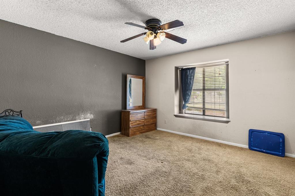 1502 Hinchliffe Road Mexia, TX 76667 - Photo 15 of 40 Bedroom with a textured ceiling, baseboards, carpet, ceiling fan, and a textured wall