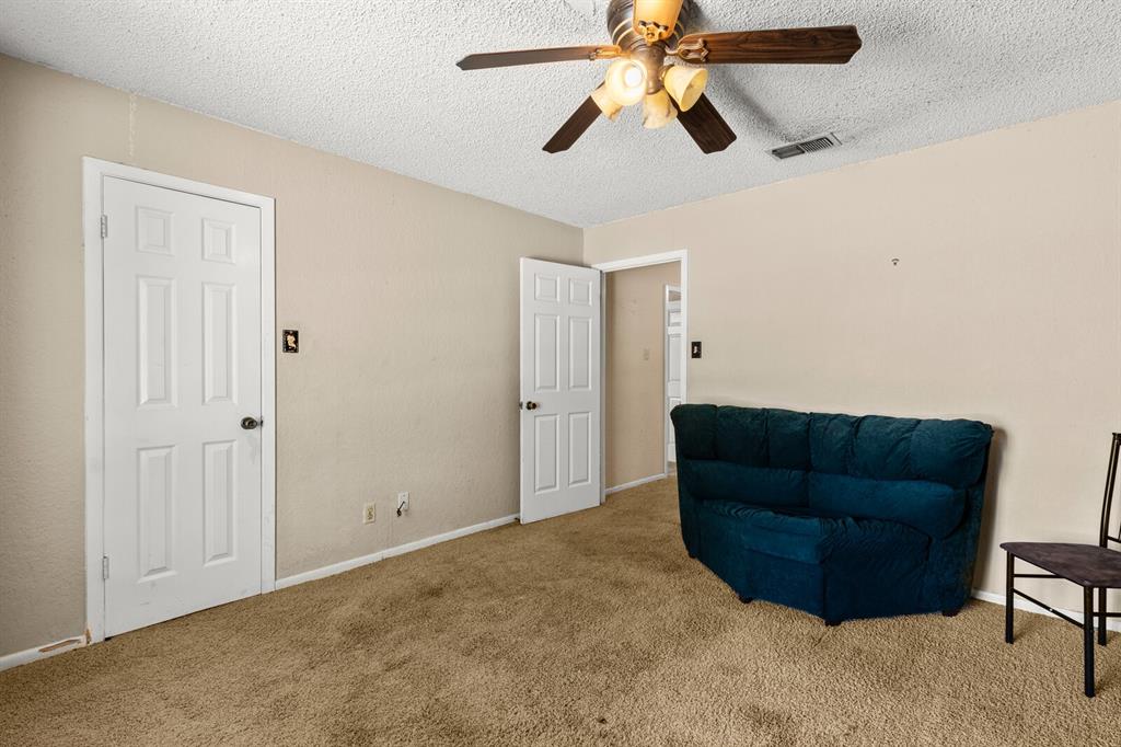 1502 Hinchliffe Road Mexia, TX 76667 - Photo 16 of 40 Living area featuring a ceiling fan, a textured ceiling, visible vents, and carpet