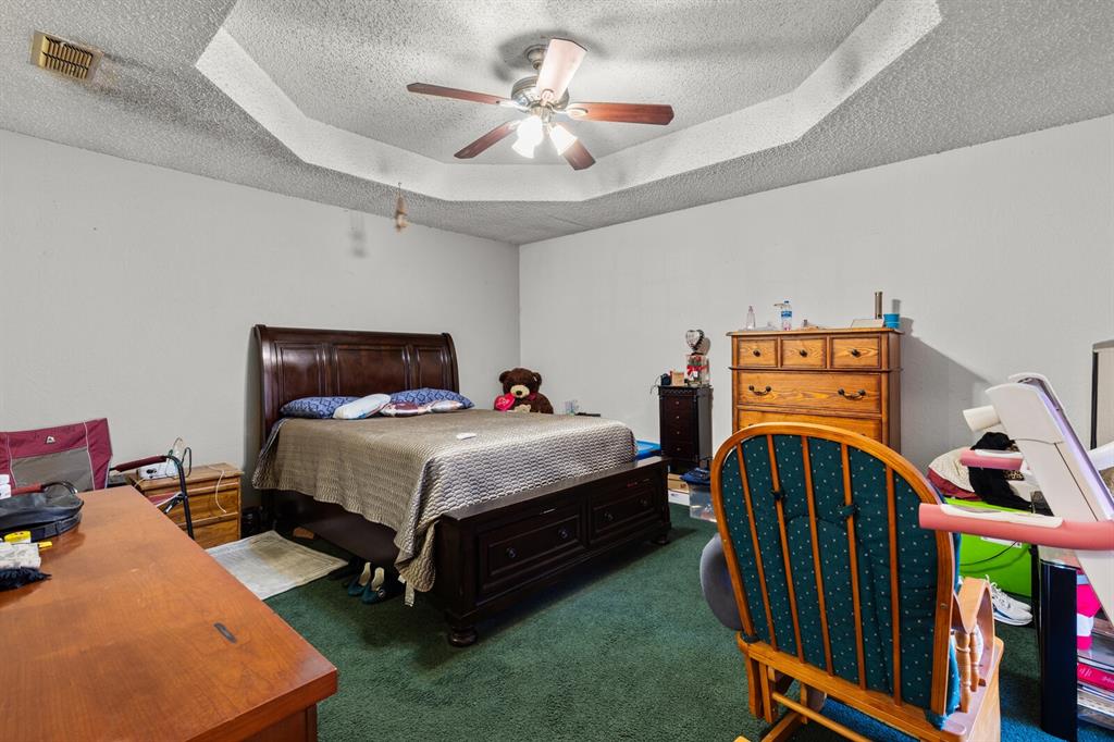 1502 Hinchliffe Road Mexia, TX 76667 - Photo 17 of 40 Carpeted bedroom featuring ceiling fan, visible vents, a textured ceiling, and a raised ceiling