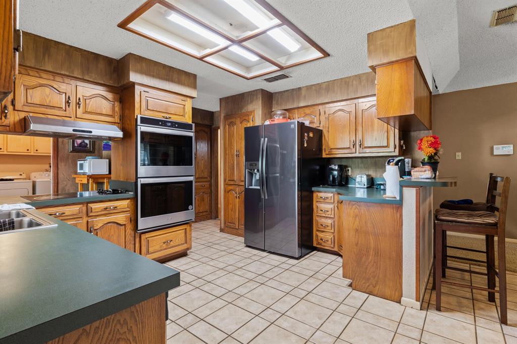 1502 Hinchliffe Road Mexia, TX 76667 - Photo 21 of 40 Kitchen with washing machine and clothes dryer, a kitchen breakfast bar, stainless steel appliances, a peninsula, and visible vents