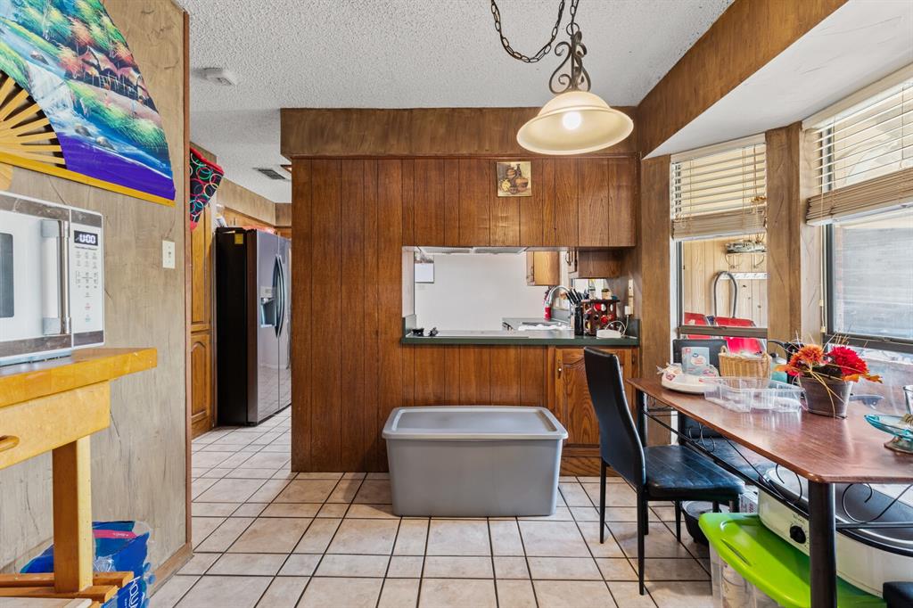 1502 Hinchliffe Road Mexia, TX 76667 - Photo 24 of 40 Kitchen featuring a sink, a textured ceiling, brown cabinets, light tile patterned flooring, and stainless steel fridge