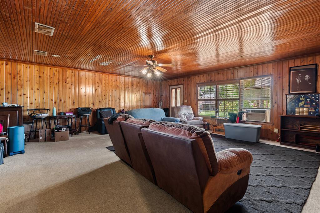 1502 Hinchliffe Road Mexia, TX 76667 - Photo 26 of 40 Living room with wooden walls, visible vents, a ceiling fan, wooden ceiling, and carpet flooring