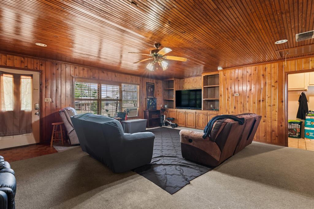 1502 Hinchliffe Road Mexia, TX 76667 - Photo 27 of 40 Carpeted living room with wooden walls, visible vents, and ceiling fan