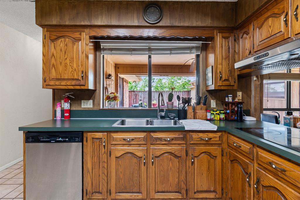 1502 Hinchliffe Road Mexia, TX 76667 - Photo 29 of 40 Kitchen featuring black electric cooktop, dishwasher, light tile patterned floors, a sink, and brown cabinetry