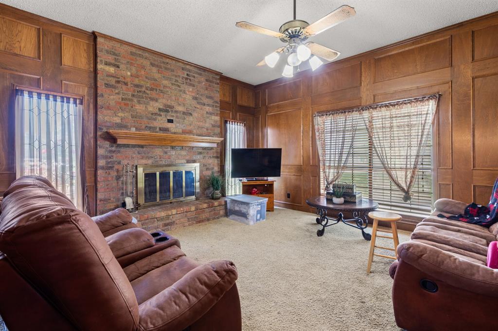 1502 Hinchliffe Road Mexia, TX 76667 - Photo 39 of 40 Living area with carpet, a brick fireplace, wood walls, and a wealth of natural light