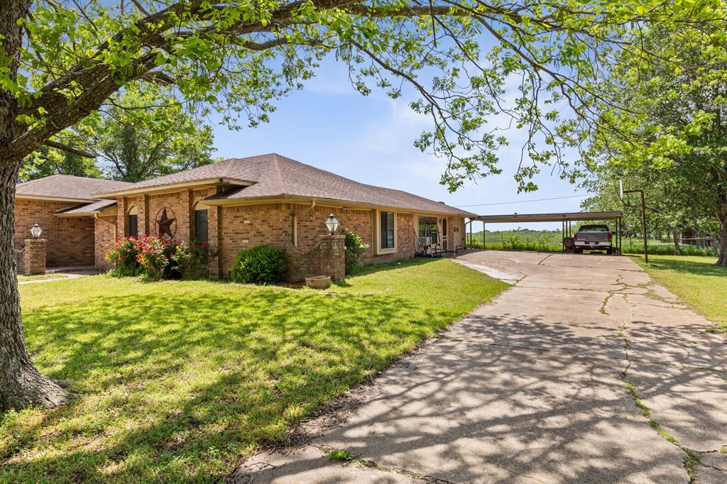 1502 Hinchliffe Road Mexia, TX 76667 - Photo 6 of 40 Ranch-style home featuring brick siding, a shingled roof, a front yard, and a carport