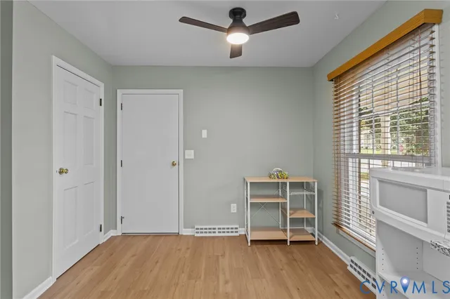 a view of an empty room with a window and wooden floor