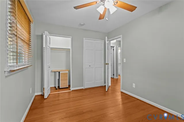 a view of an empty room with window and wooden floor