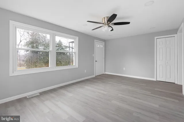 a view of empty room with wooden floor and fan