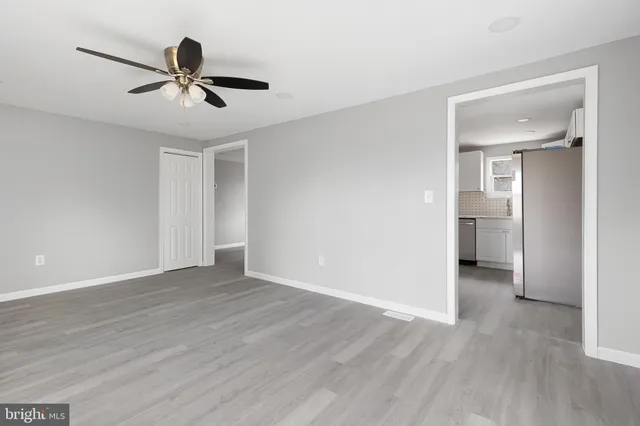 a view of empty room with wooden floor and ceiling fan