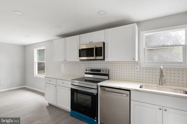 a kitchen with sink a microwave a stove and cabinets