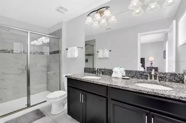 a bathroom with a granite countertop sink a toilet a mirror and shower