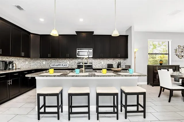 a kitchen with granite countertop a stove a sink a microwave a dining table and chairs