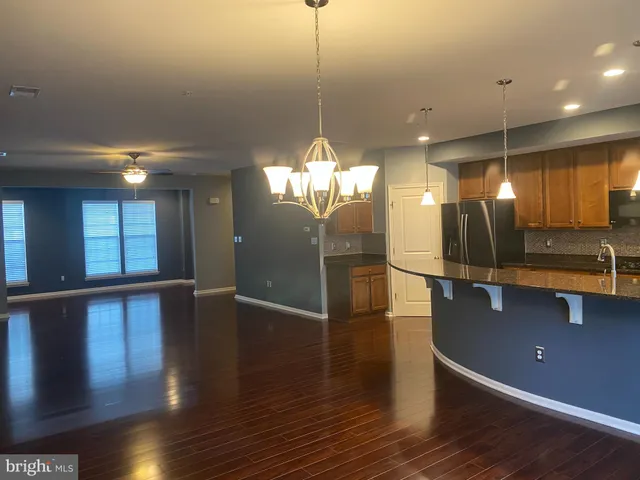 a kitchen with stainless steel appliances granite countertop a refrigerator a sink and a wooden floors