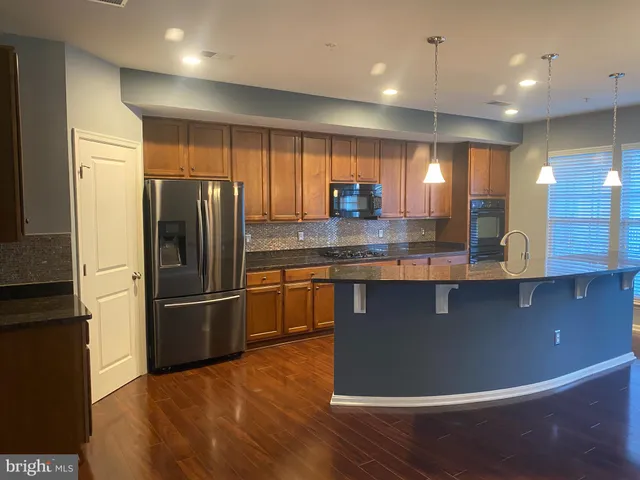 a kitchen with stainless steel appliances granite countertop a refrigerator a sink and a stove