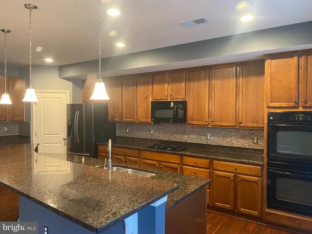 a kitchen with kitchen island granite countertop a sink a counter top space appliances and cabinets