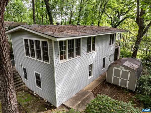 a view of a house with a yard plants and large tree