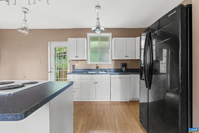 a kitchen with stainless steel appliances granite countertop a refrigerator a sink dishwasher a stove and white cabinets with wooden floor