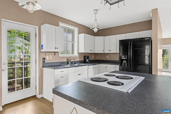 a kitchen with granite countertop a stove a sink dishwasher and a refrigerator with wooden floor