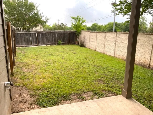 a view of a backyard with wooden fence and a large tree