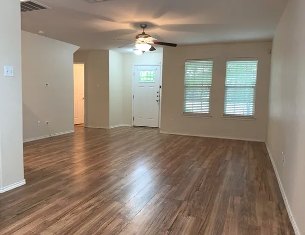 an empty room with wooden floor and windows