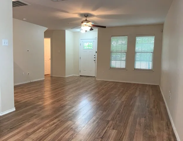 an empty room with wooden floor and windows