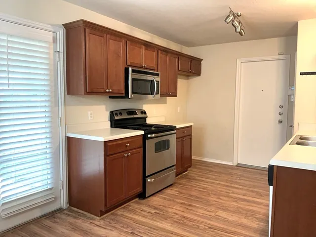 a kitchen with stainless steel appliances granite countertop a stove a sink and a refrigerator with wooden floors