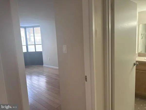 a view of hallway with window and wooden floor